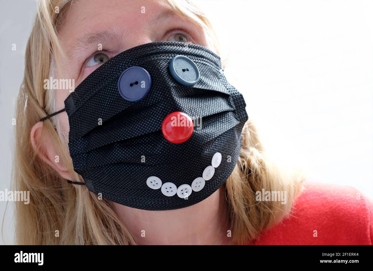 donna che indossa una faccia nera del coronavirus del giorno del naso rosso maschera Foto Stock