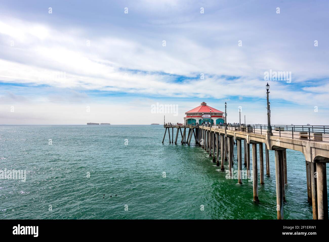 L'iconico edificio dal tetto rosso alla fine del molo di Huntington Beach, dove le persone pescano, vengono a mangiare e godersi il caldo sole. Foto Stock
