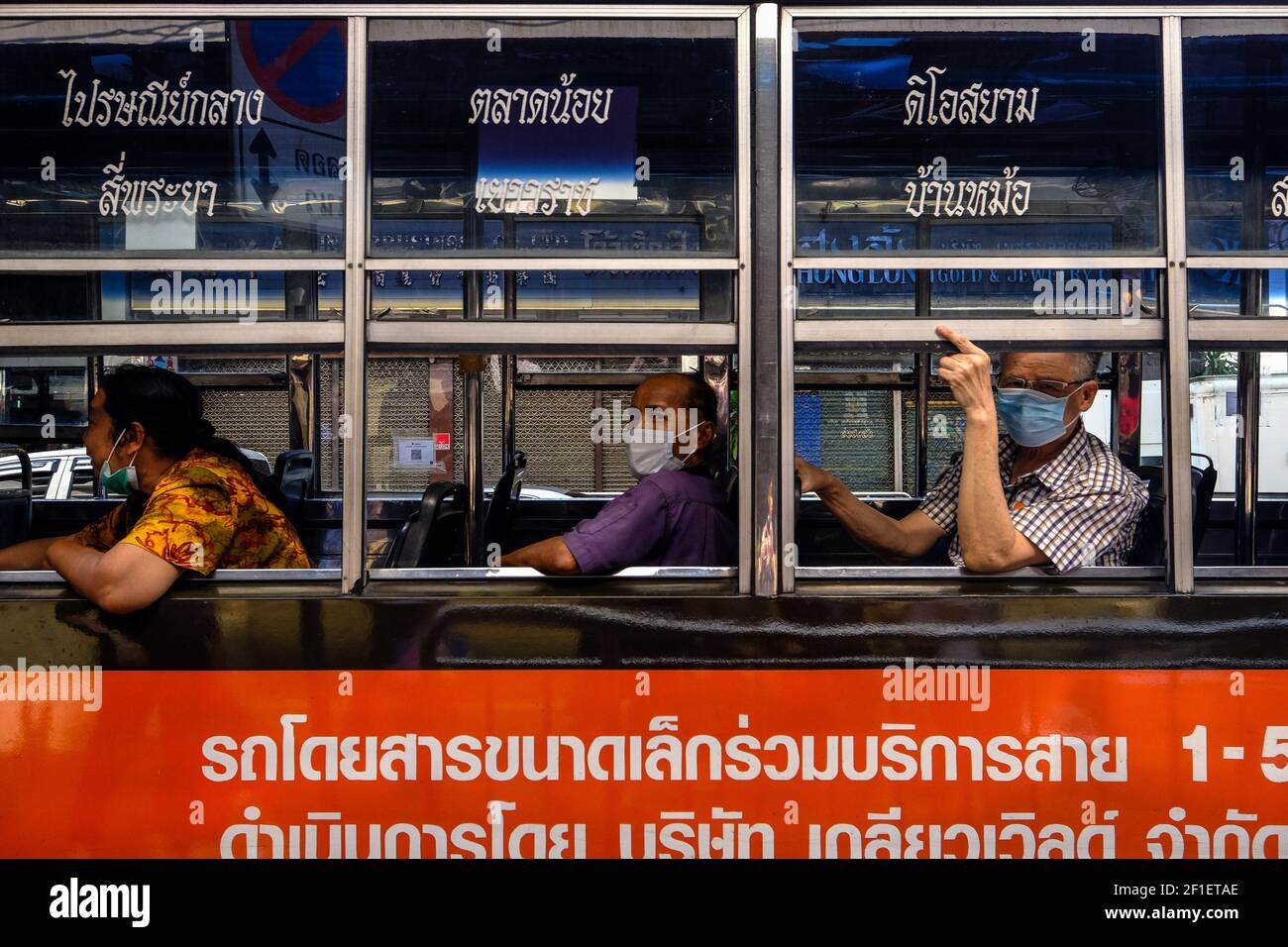 I passeggeri che indossano maschere durante il Covid 19 Pandemic si affacciano dalla finestra di un autobus di Bangkok a Chinatown, Bangkok, Thailandia Foto Stock