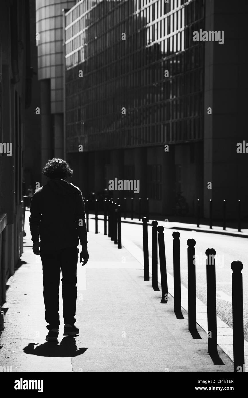 Paesaggio urbano parigino con una silhouette maschile giovane e irriconoscibile (vista posteriore) vicino a Place de la Bastille. Parigi, Francia. Foto in bianco e nero Foto Stock