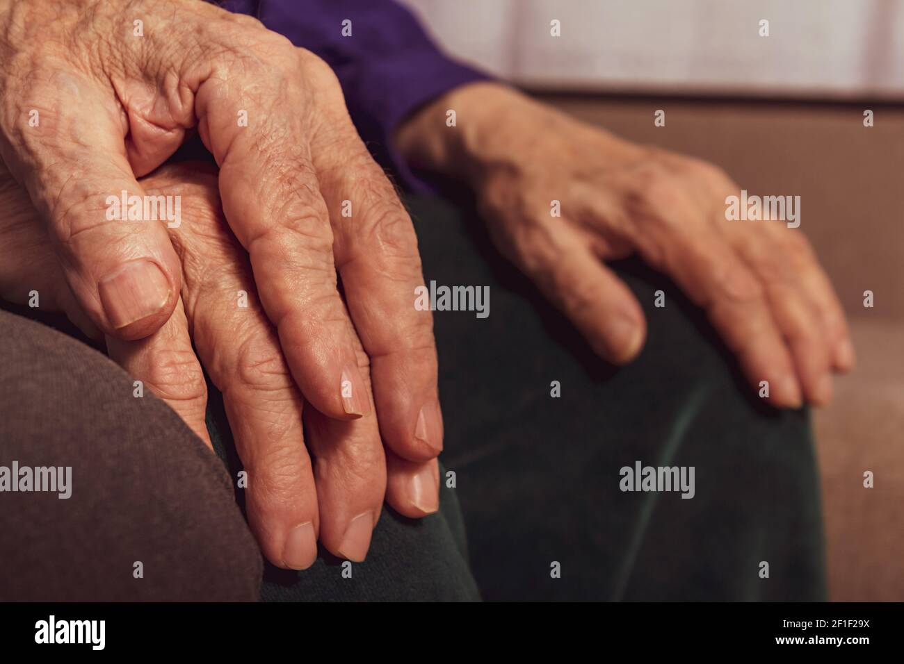 Coppie anziane. Primo piano mani anziane. Mani di uomo e donna caucasica irriconoscibili. Vecchia coppia matrimoniale sul divano. Foto Stock