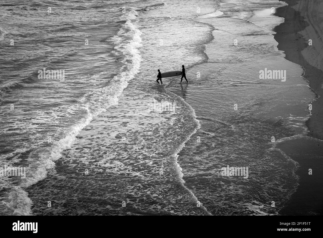 Due surfisti camminano con la tavola da surf verso il mare. Foto Stock