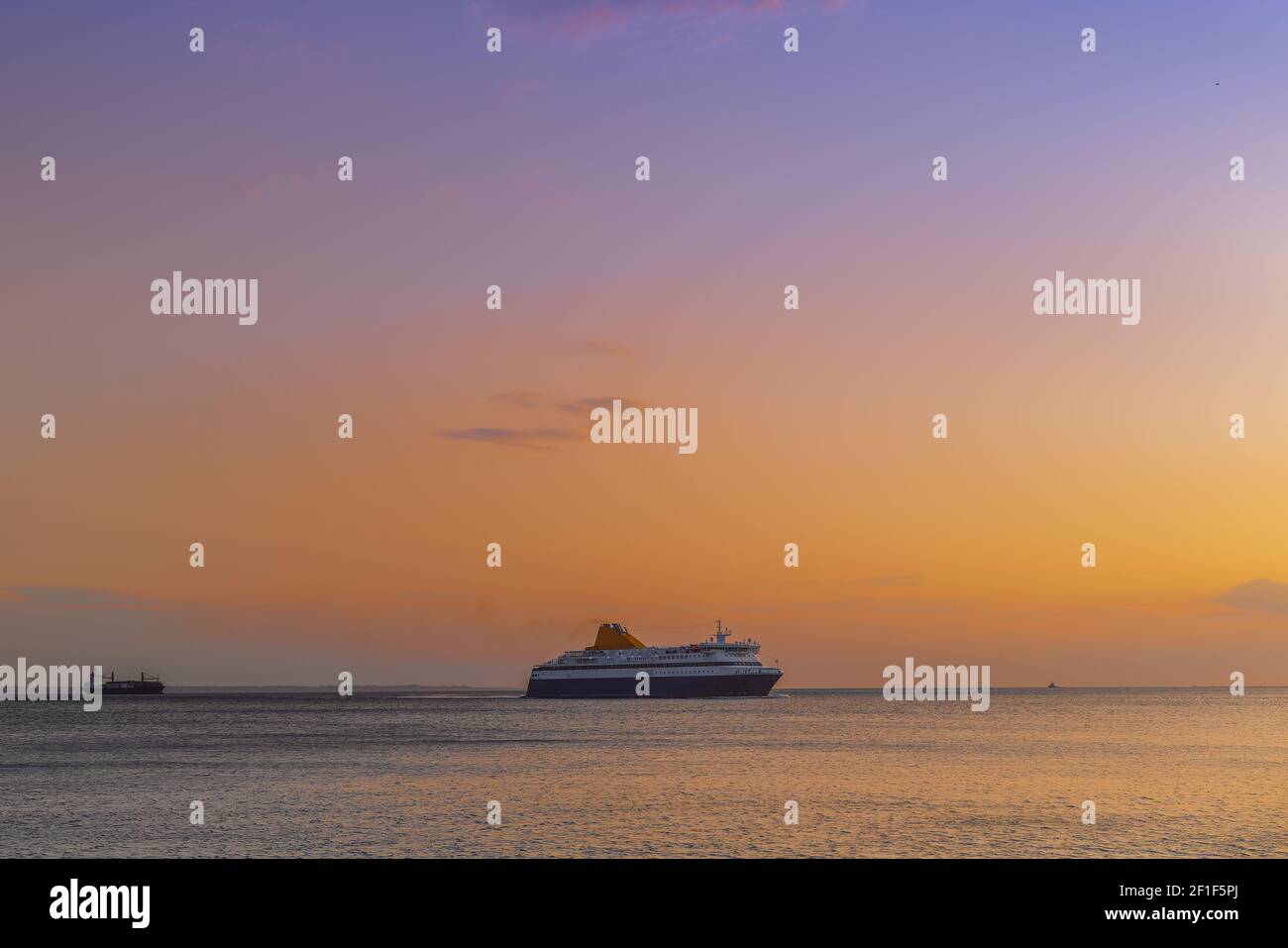 Nave da passeggeri che naviga verso il porto marittimo della città al tramonto a Salonicco, Grecia. Vista serale della barca commerciale in attesa di entrare nel tranquillo porto. Foto Stock