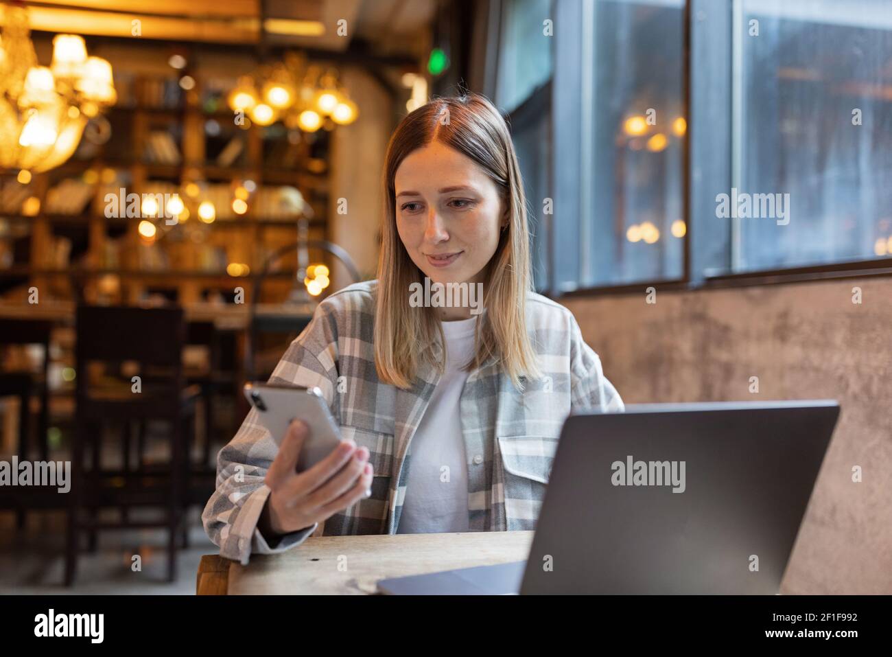 Giovane donna caucasica di affari con i capelli biondi che lavorano sul laptop nel caffè. Studente universitario utilizzando la tecnologia , formazione online, freelance Foto Stock