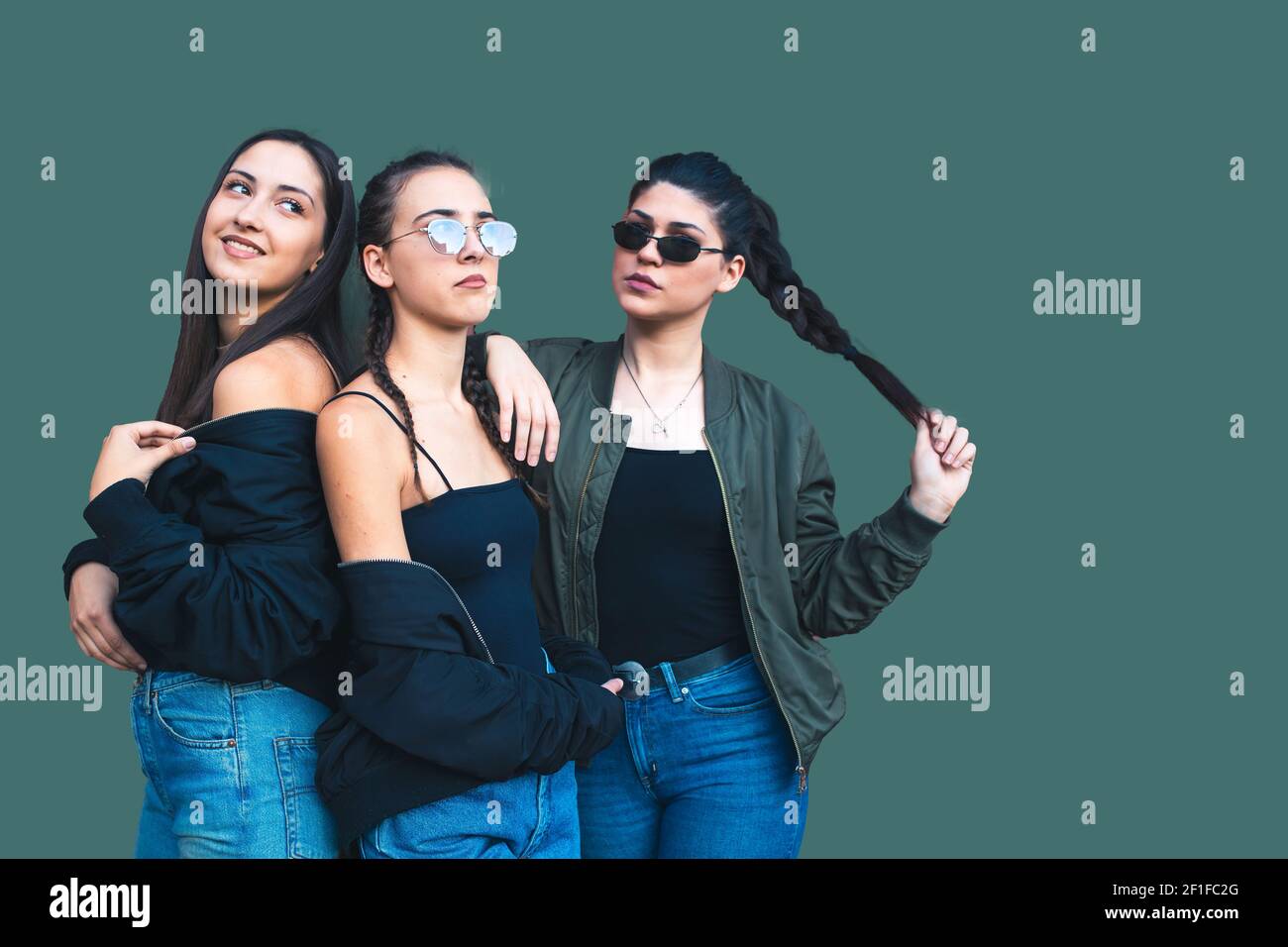 Tre belle ragazze adolescenti brunette isolate su sfondo verde. Stile casual alla moda, giacche nere Foto Stock