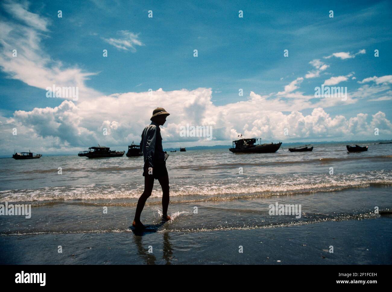 Un pescatore con barca da pesca sullo sfondo, villaggio costiero, Vietnam del Nord, giugno 1980 Foto Stock