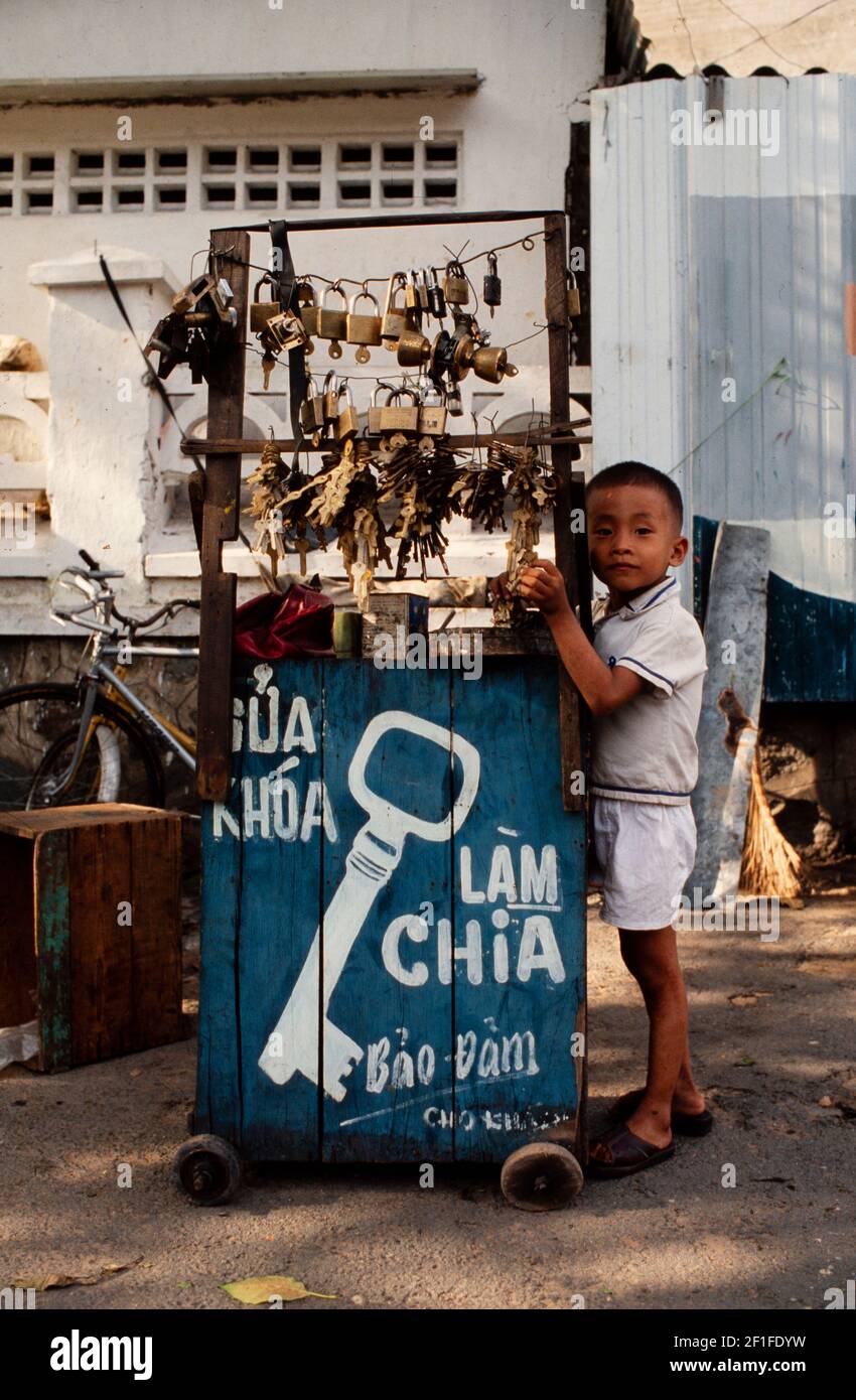 Un giovane ragazzo che consta la chiave di strada del suo genitore, ho Chi Minh City, Vietnam, giugno 1980 Foto Stock