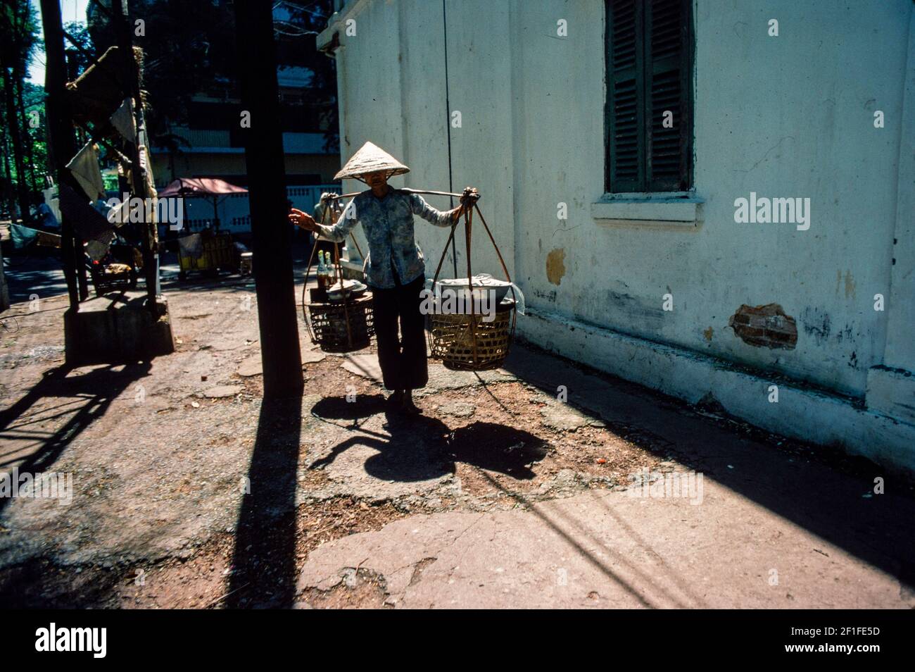 Una donna che porta cibo di strada per allestire la sua stalla, ho Chi Minh City, Vietnam, giugno 1980 Foto Stock