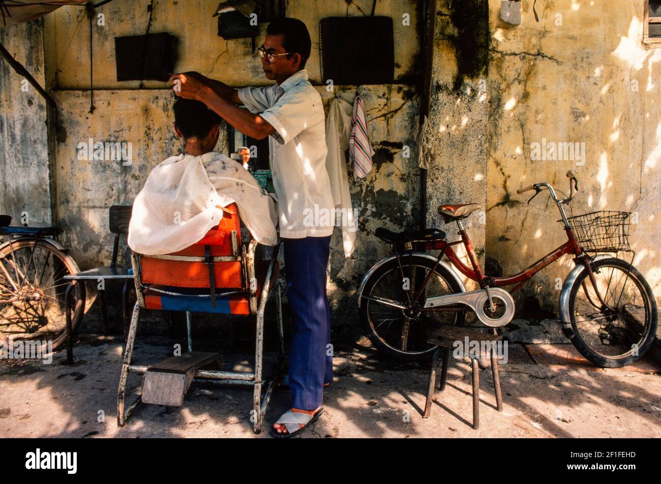 Un barbiere di strada, ho Chi Minh City, Vietnam, giugno 1980 Foto Stock