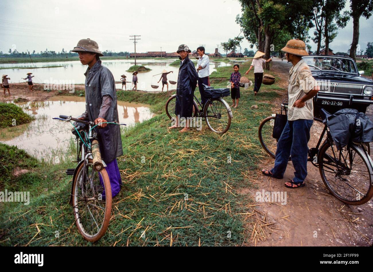 La gente che guarda gli abitanti del villaggio che pescano negli stagni di pesce con i loro cestini di pesca, Vietnam rurale del Sud, giugno 1980 Foto Stock