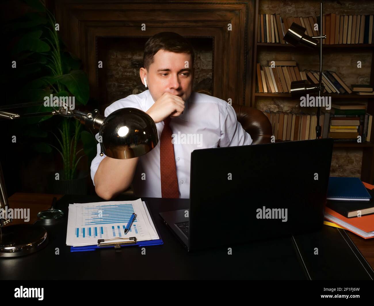 Un uomo d'affari a tarda notte comunica su Internet e guarda un computer portatile. Foto Stock
