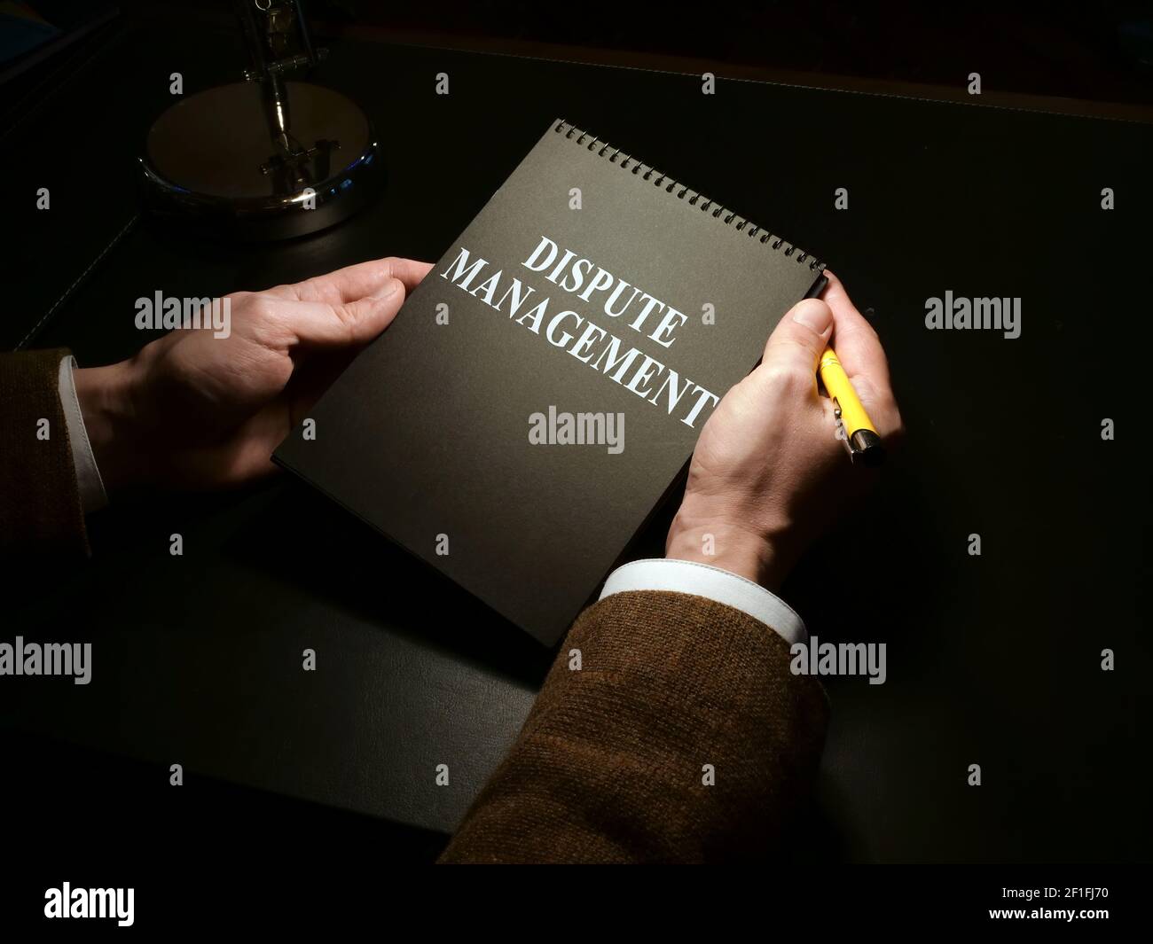 L'uomo tiene il libro di gestione di dispute nella stanza buia. Foto Stock