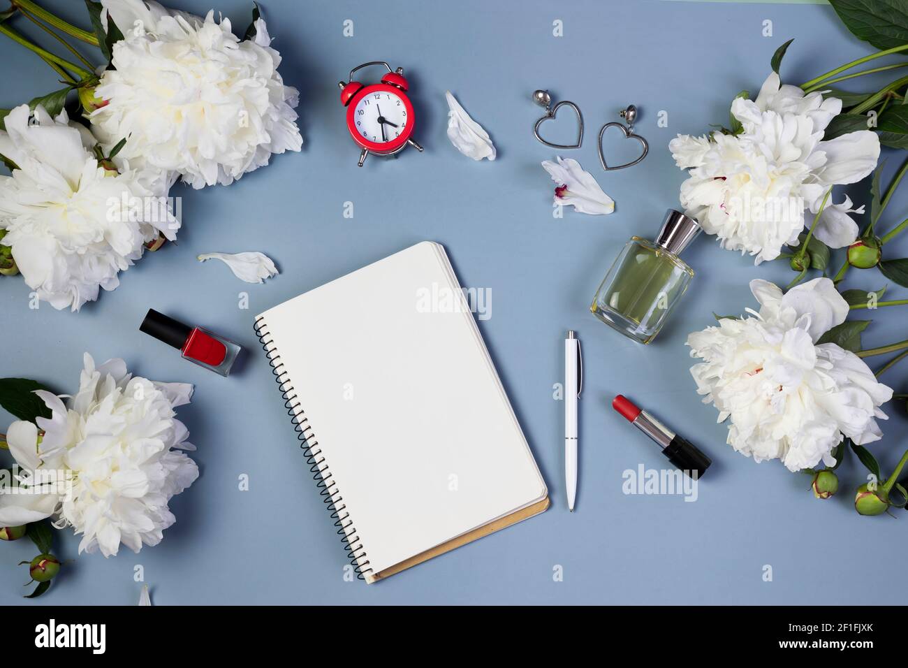 apri il notebook per scrivere piani, per fare lista o sogni con peonie fresche, sveglia, su sfondo azzurro Foto Stock