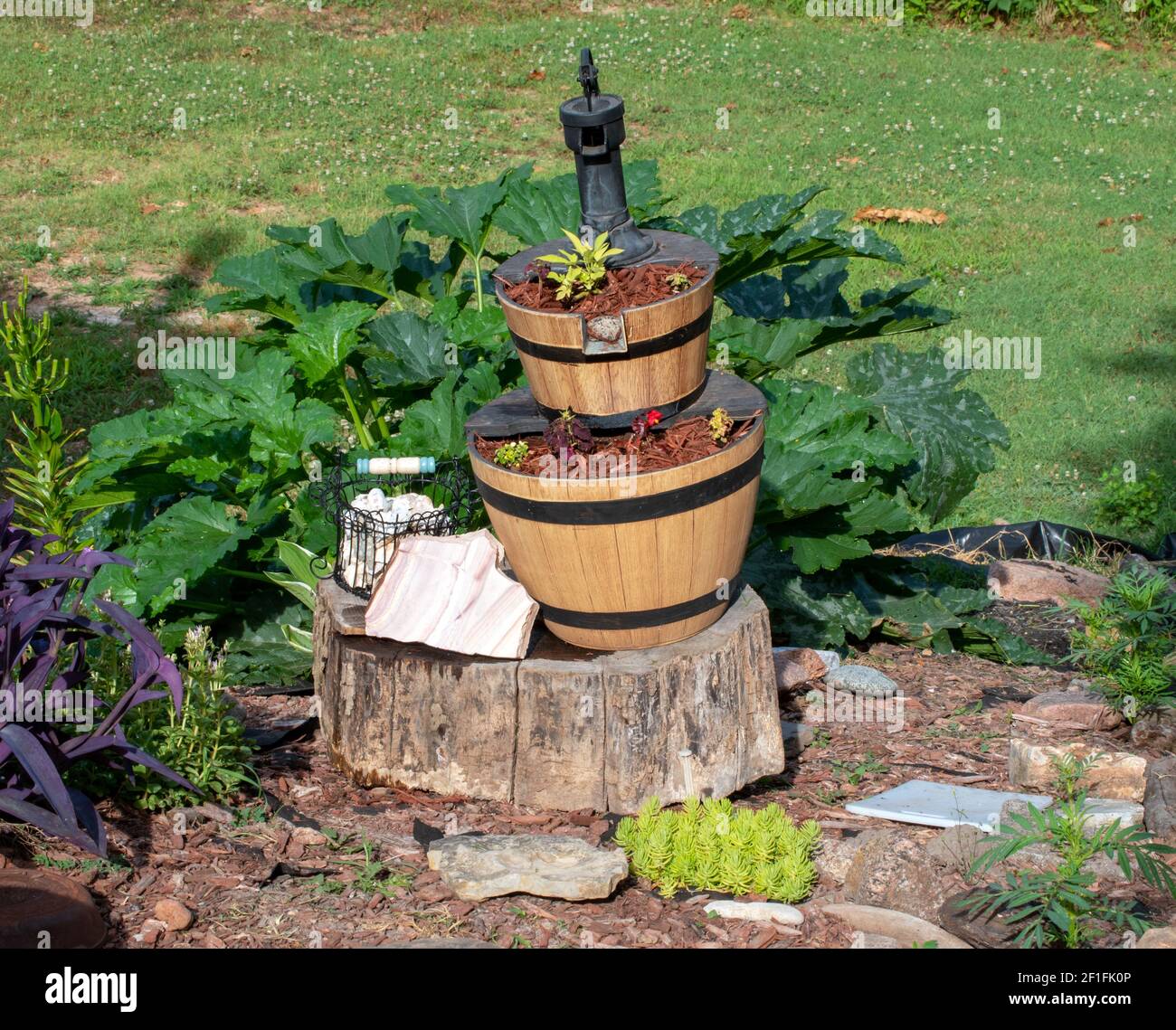 Una fontana in stile pompa di legno è stata trasformata nel punto focale di un giardino cortile nel sud-ovest del Missouri per un ornamento unico di interesse. Bokeh Foto Stock