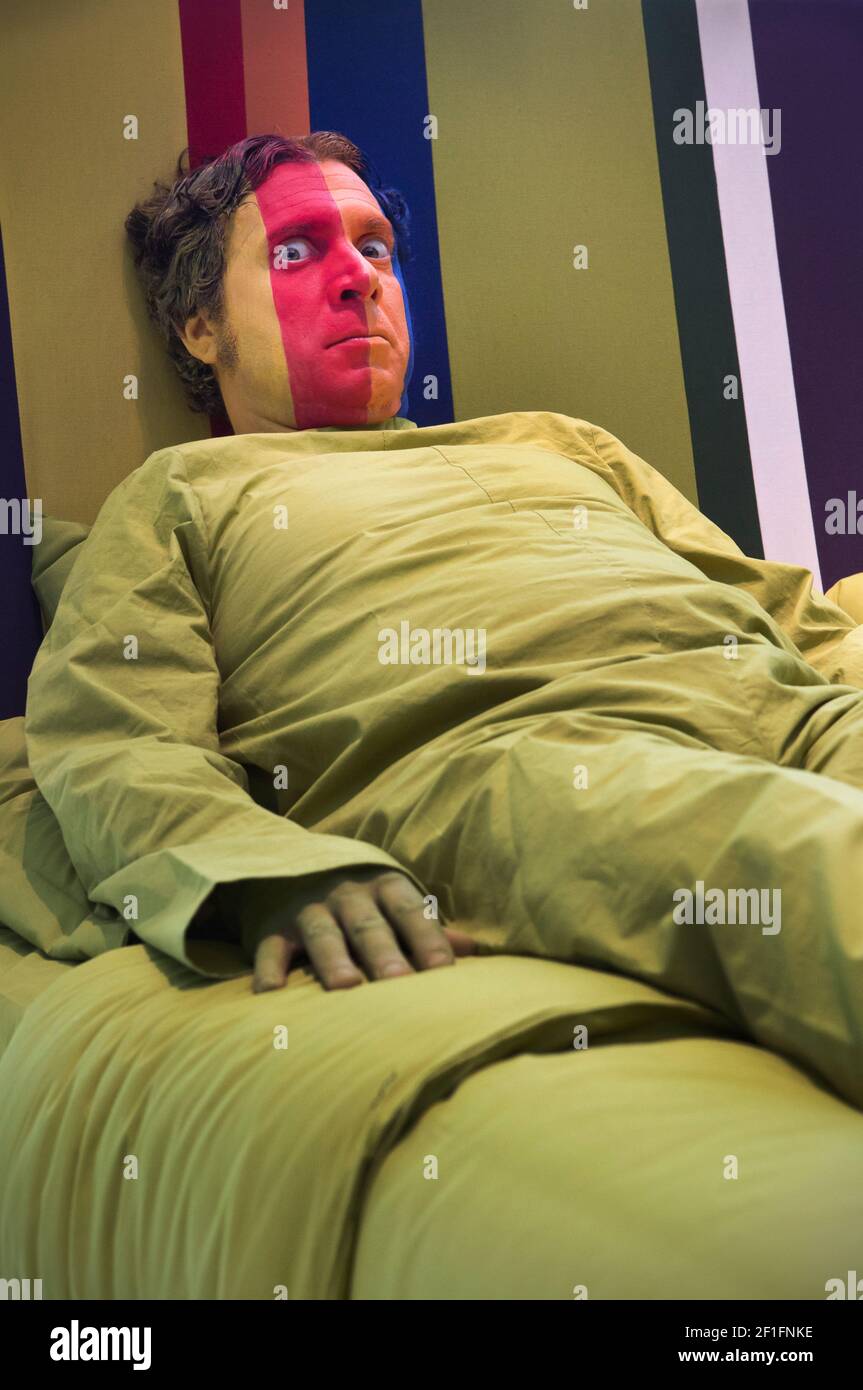 Un uomo con una faccia colorata giace in un letto enorme Foto Stock