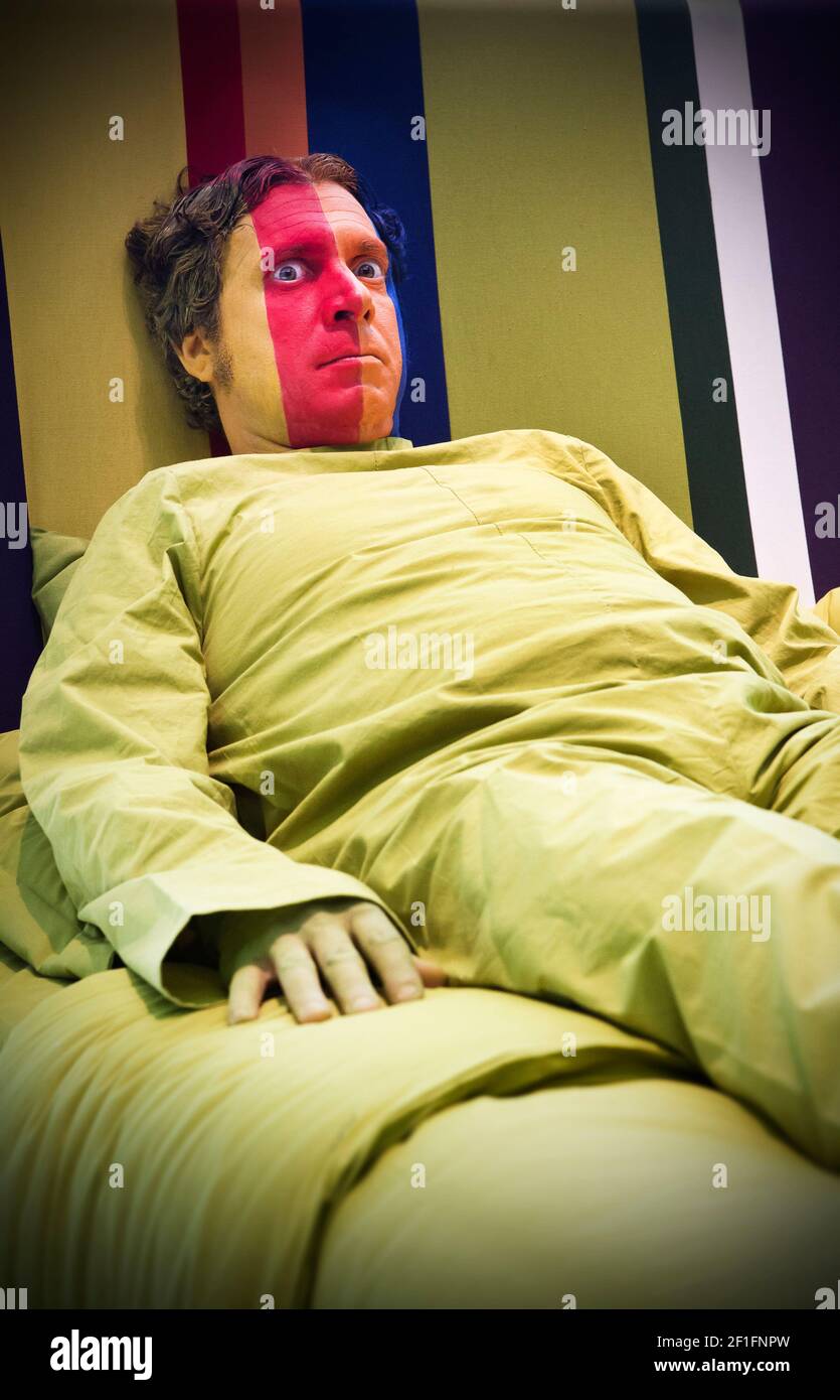 Un uomo con una faccia colorata giace in un letto enorme Foto Stock