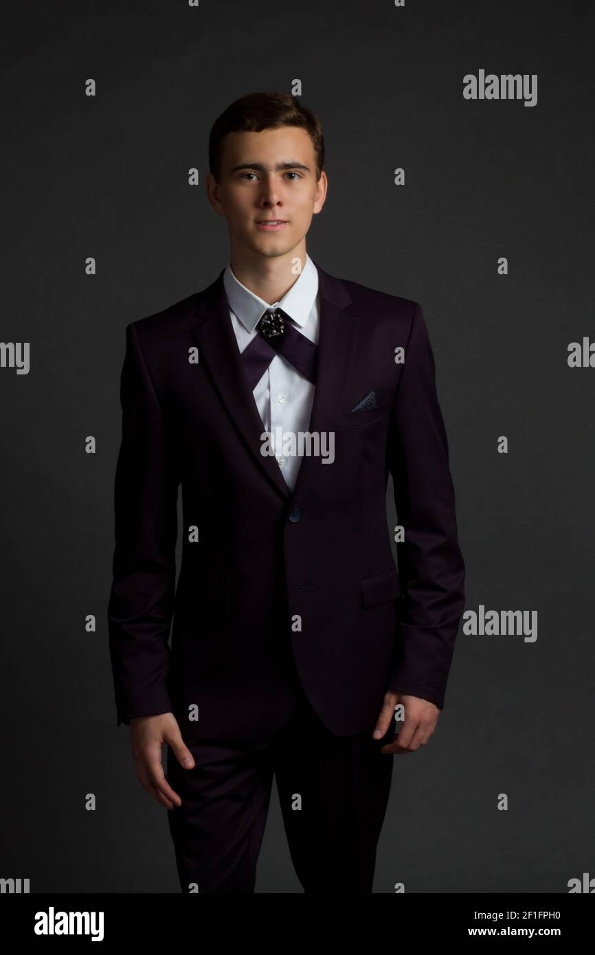un giovane uomo dai capelli scuri con camicia bianca, abito viola scuro e  cravatta a fiocco a croce maschile Foto stock - Alamy