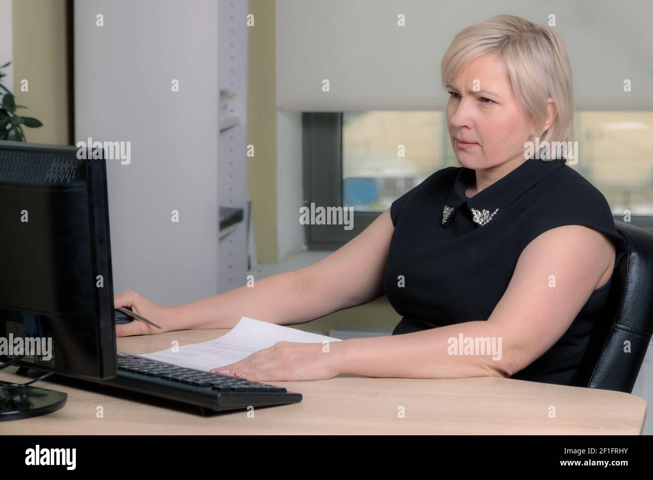 Una direttrice femminile che lavora in un ufficio è seduta a un tavolo, analizzando le statistiche aziendali, controllando i documenti. Primo piano. Foto Stock