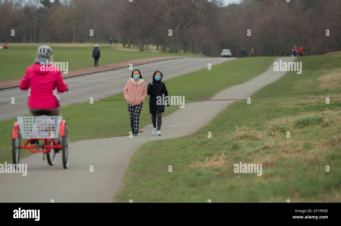 Edimburgo, Scozia, Regno Unito. 8 Marzo 2021. Due donne in maschera che camminano verso una donna su un tricilce sulla pista ciclabile di Arthur's Seat, Holyrood Park, Edimburgo, 8 marzo 2021. Credit: Gayle McIntyre/Alamy Live News Foto Stock