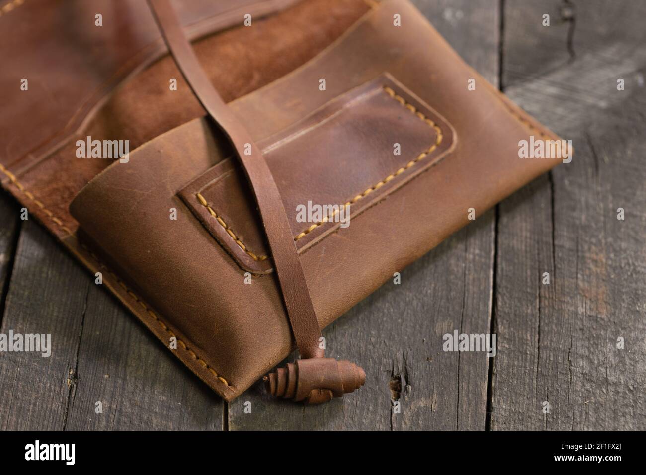 Marroncino moda di cuoio di tabacco su sfondo di legno. Prodotto artigianale fatto a mano. Foto Stock