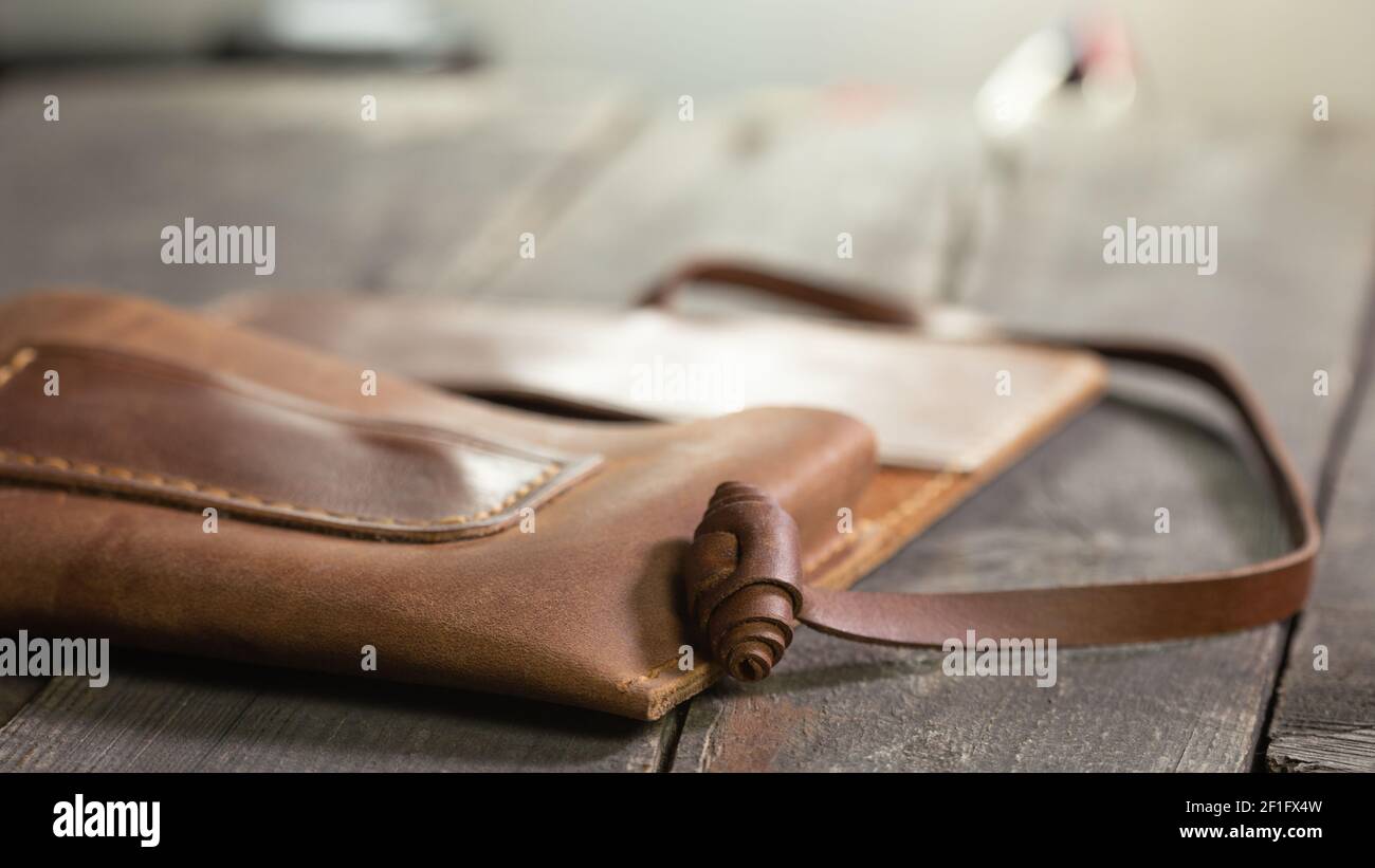 Marroncino moda di cuoio di tabacco su sfondo di legno. Prodotto artigianale fatto a mano. Foto Stock