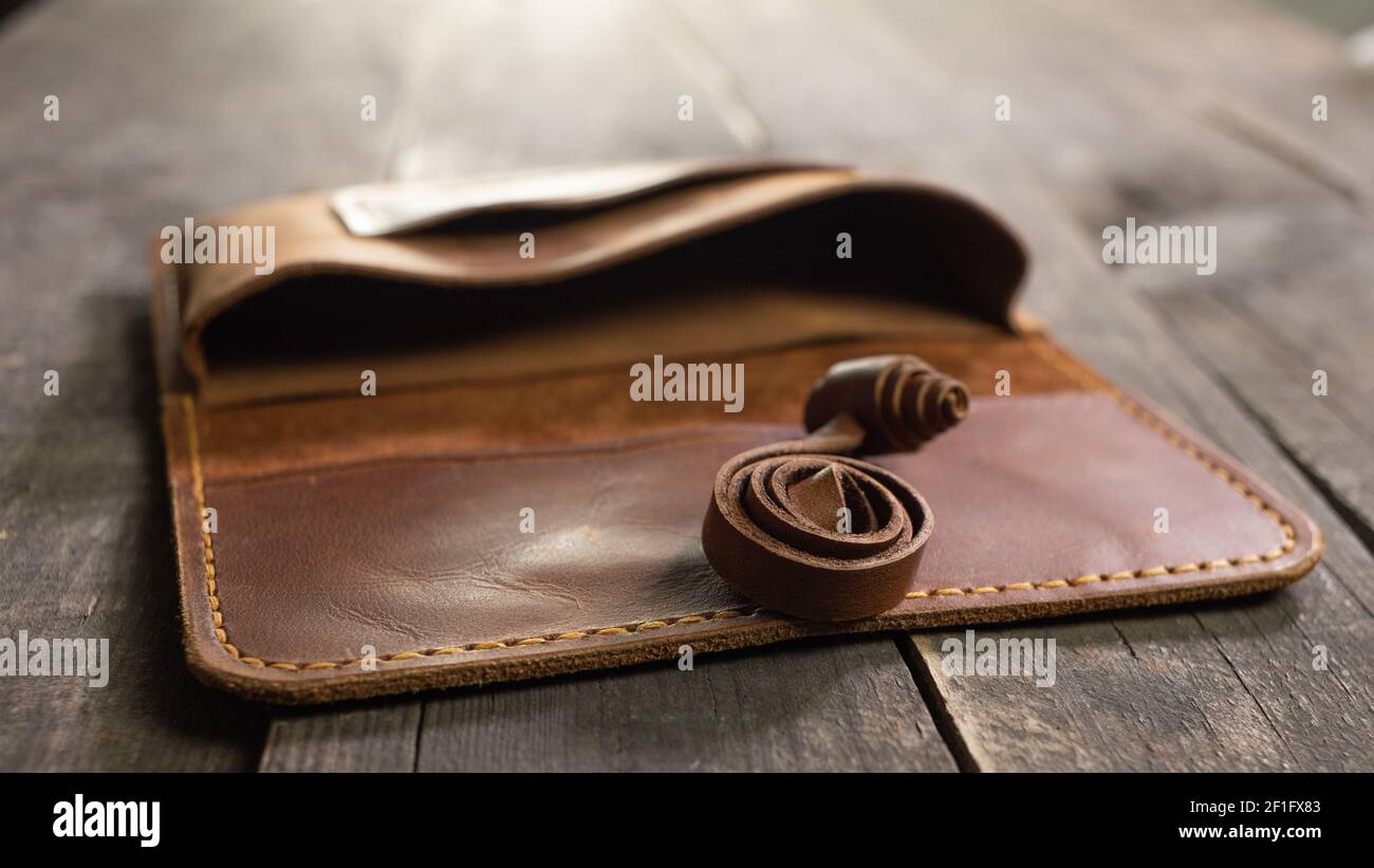Marroncino moda di cuoio di tabacco su sfondo di legno. Prodotto artigianale fatto a mano. Foto Stock