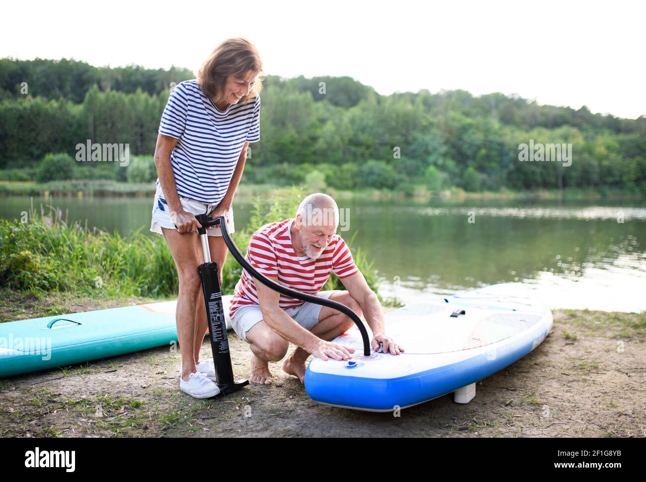 La coppia anziana si prepara per il paddleboarding sul lago in estate. Foto Stock