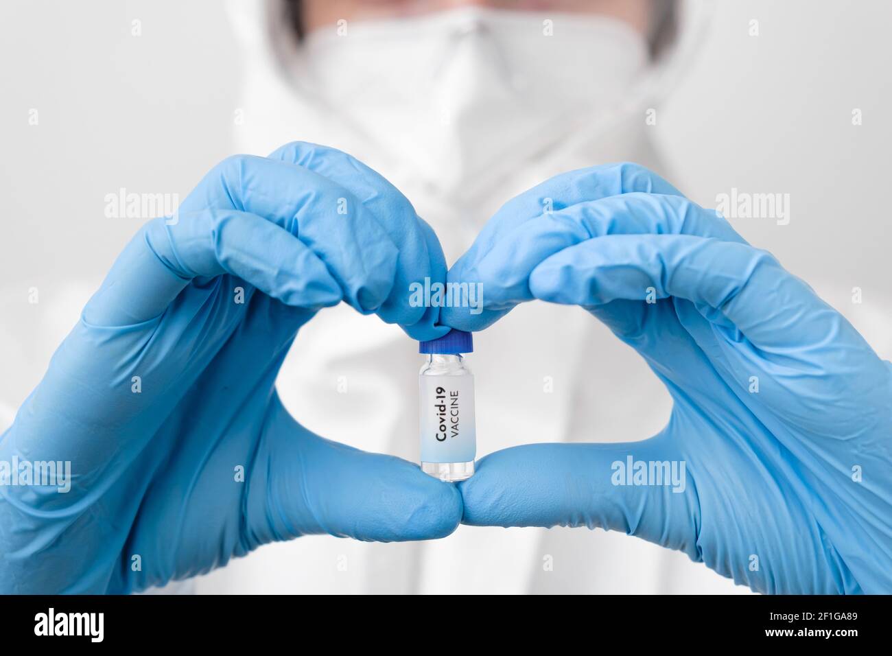 Vaccino Covid-19 in medici o infermieri mani sotto forma di cuore in guanti di gomma blu. Prevenzione di sars-COV-2 o Covid-19 Foto Stock
