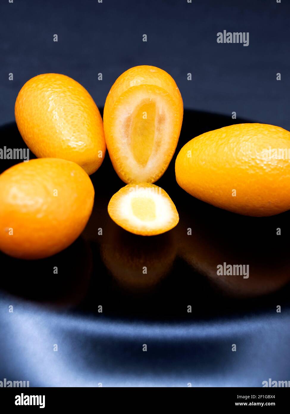 Kumquat giallo maturo su sfondo nero. Frutta esotica. Foto Stock