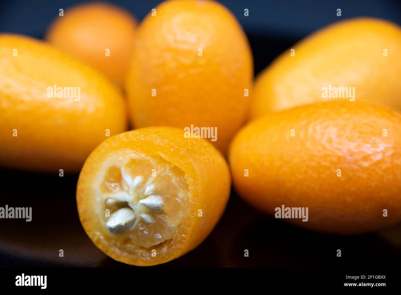 Kumquat giallo maturo su sfondo nero. Frutta esotica. Foto Stock