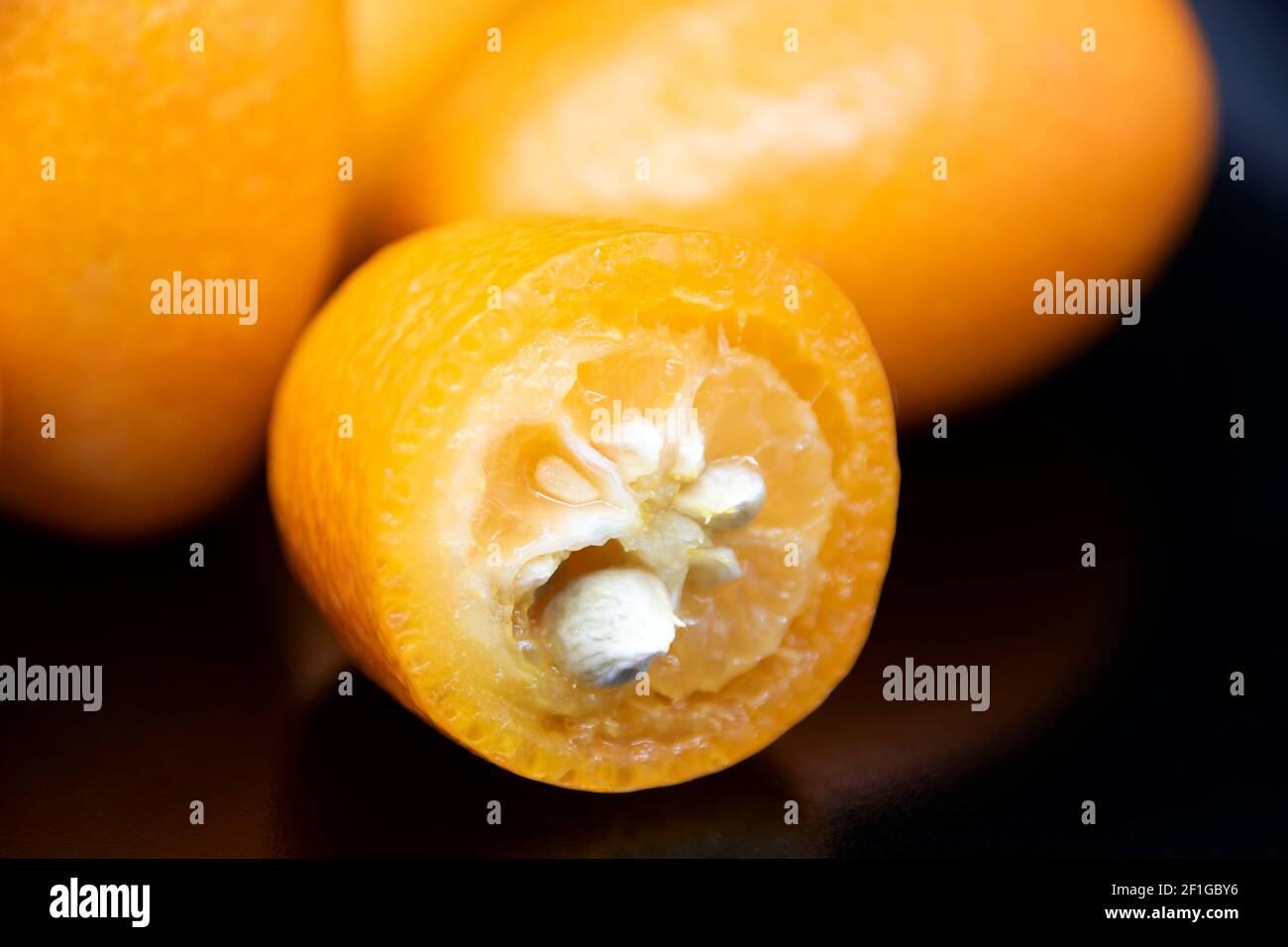 Kumquat giallo maturo su sfondo nero. Frutta esotica. Foto Stock