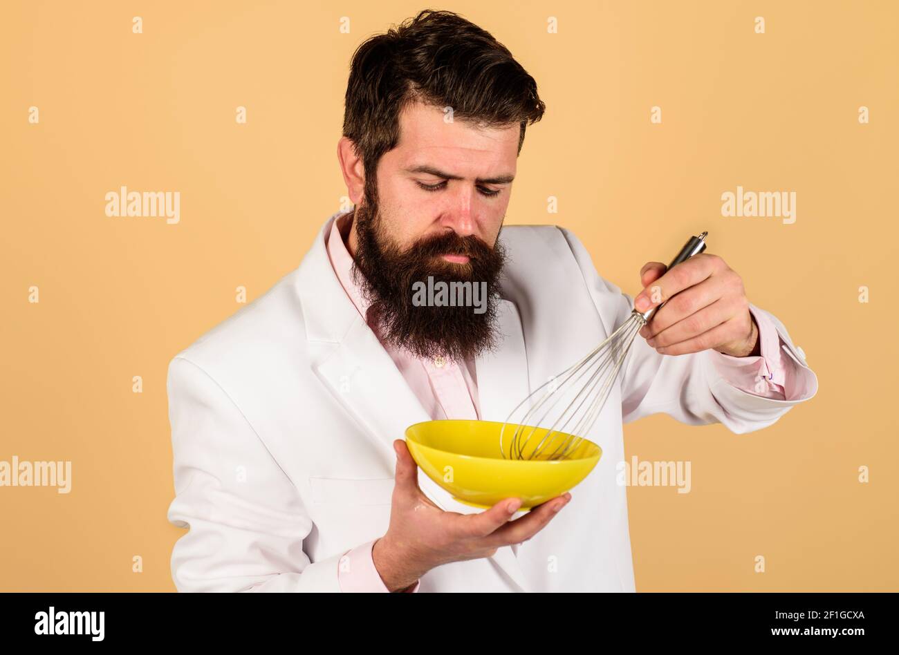Uomo bearded che prepara le uova per la colazione. Montare l'uovo nel recipiente per cucinare le omelette o l'impasto. Cucina, cucina e concetto di cucina. Foto Stock