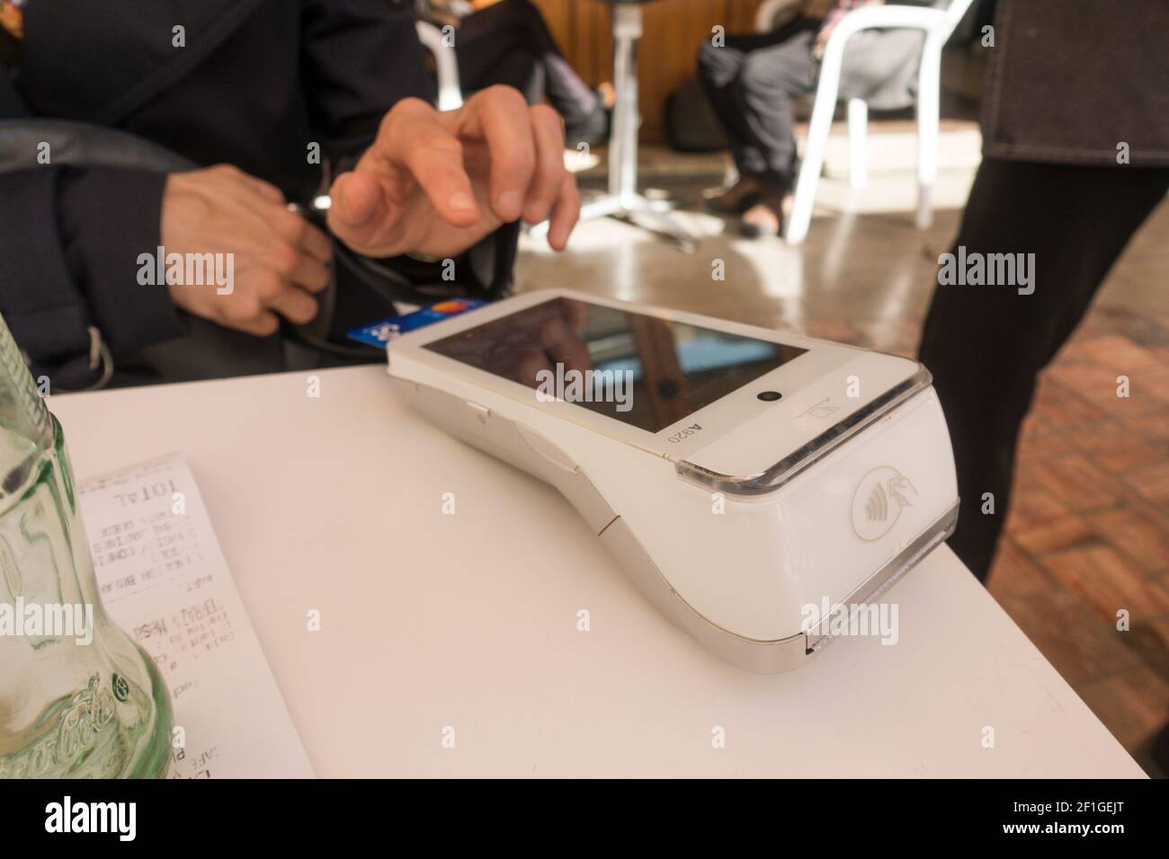 Donna autorizza un pagamento utilizzando un terminale di pagamento, terminale POS su un tavolo in ristorante. Foto Stock