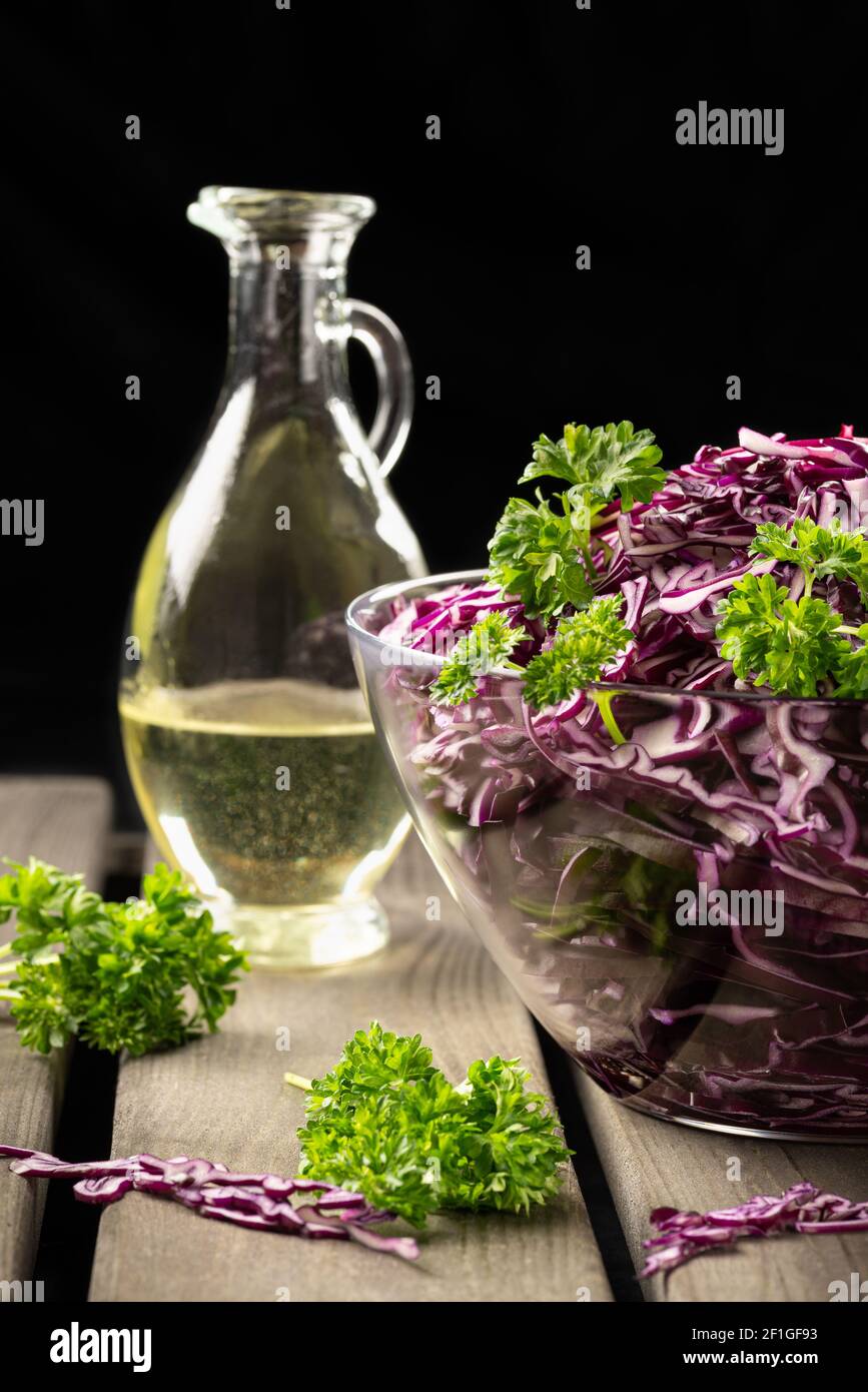 Concetto vegano, alimentazione sana. Insalata di cavolo rosso su sfondo nero, in stile rustico, profondità di campo poco profonda, fuoco selettivo Foto Stock