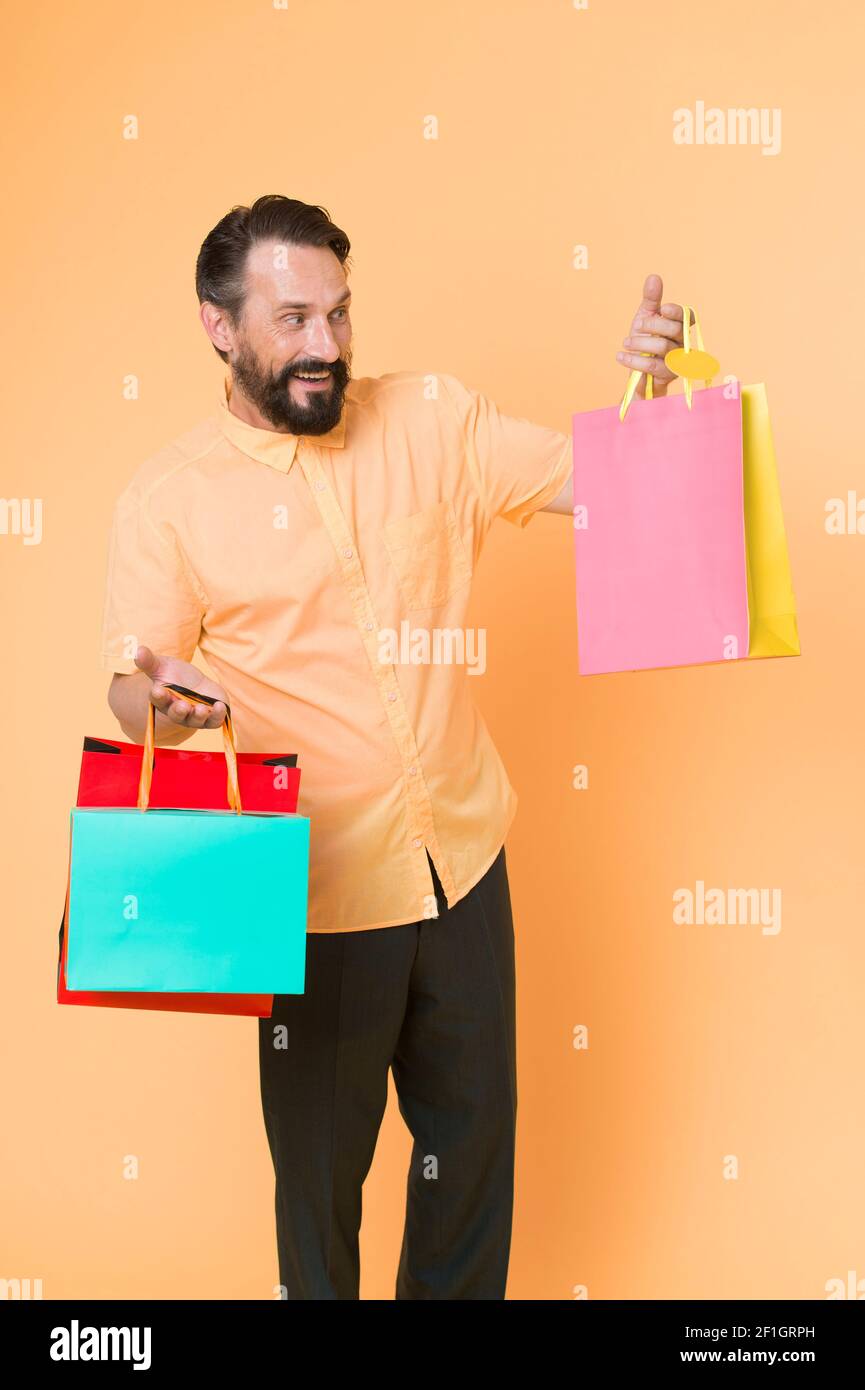 Acquista e divertiti. Shopping Addict sfondo giallo. Uomo maturo tenere borse di shopping. Buon acquirente con sacchetti di carta. Vendita e shopping. Shopping come dovrebbe essere, copia spazio. Foto Stock