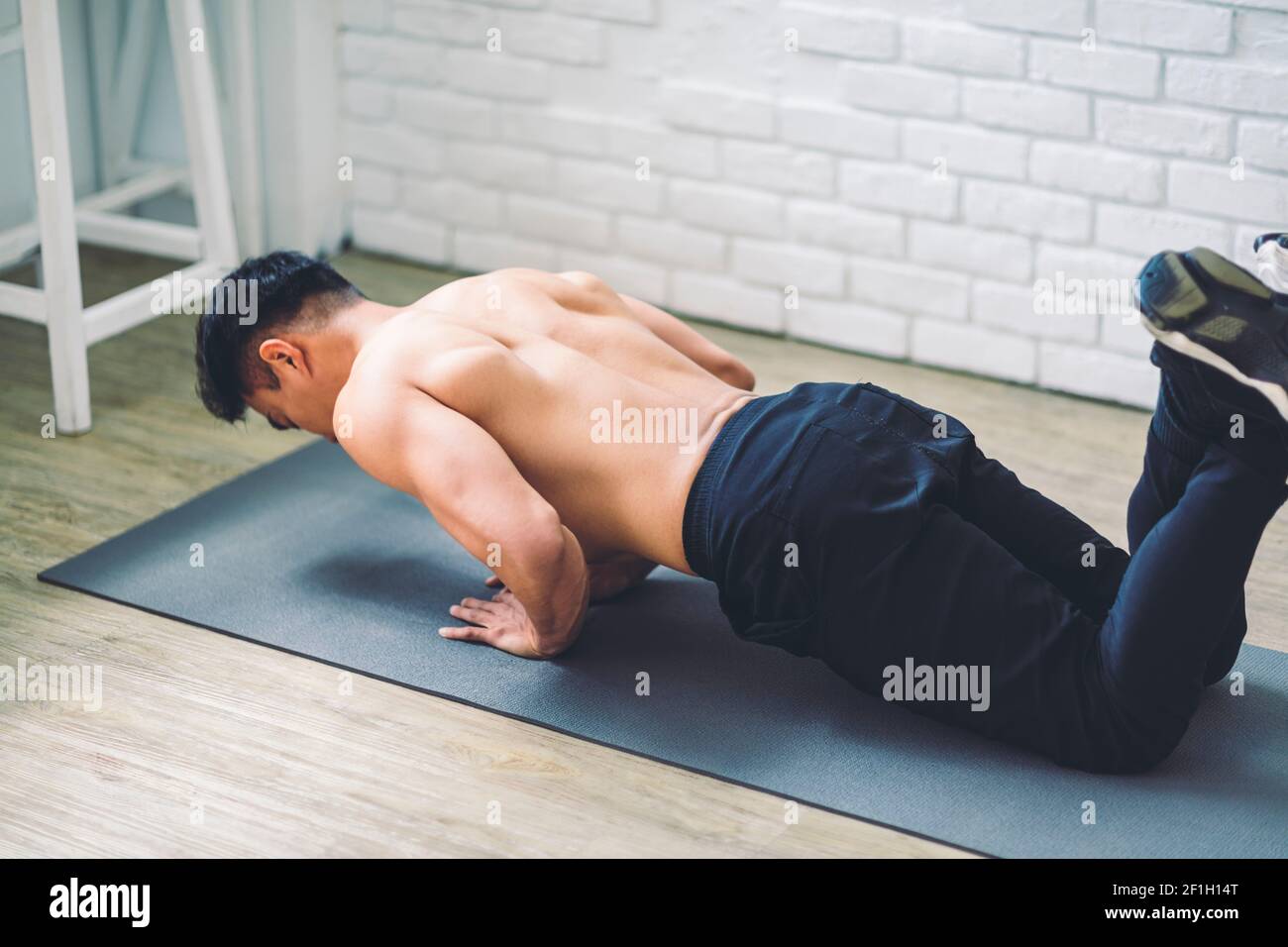 Giovane asiatico muscolare facendo esercizi sul pavimento a casa Foto Stock