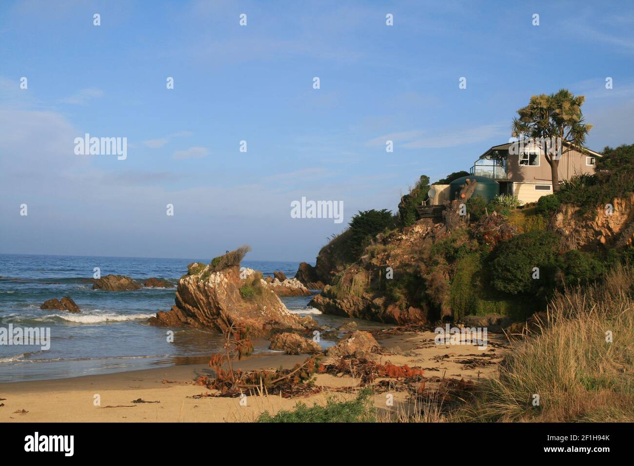 Wild South Ocean Beach con spiaggia casa sulle rocce, Nugget Lodge vicino a Nugget Point, Southland, Nuova Zelanda Foto Stock