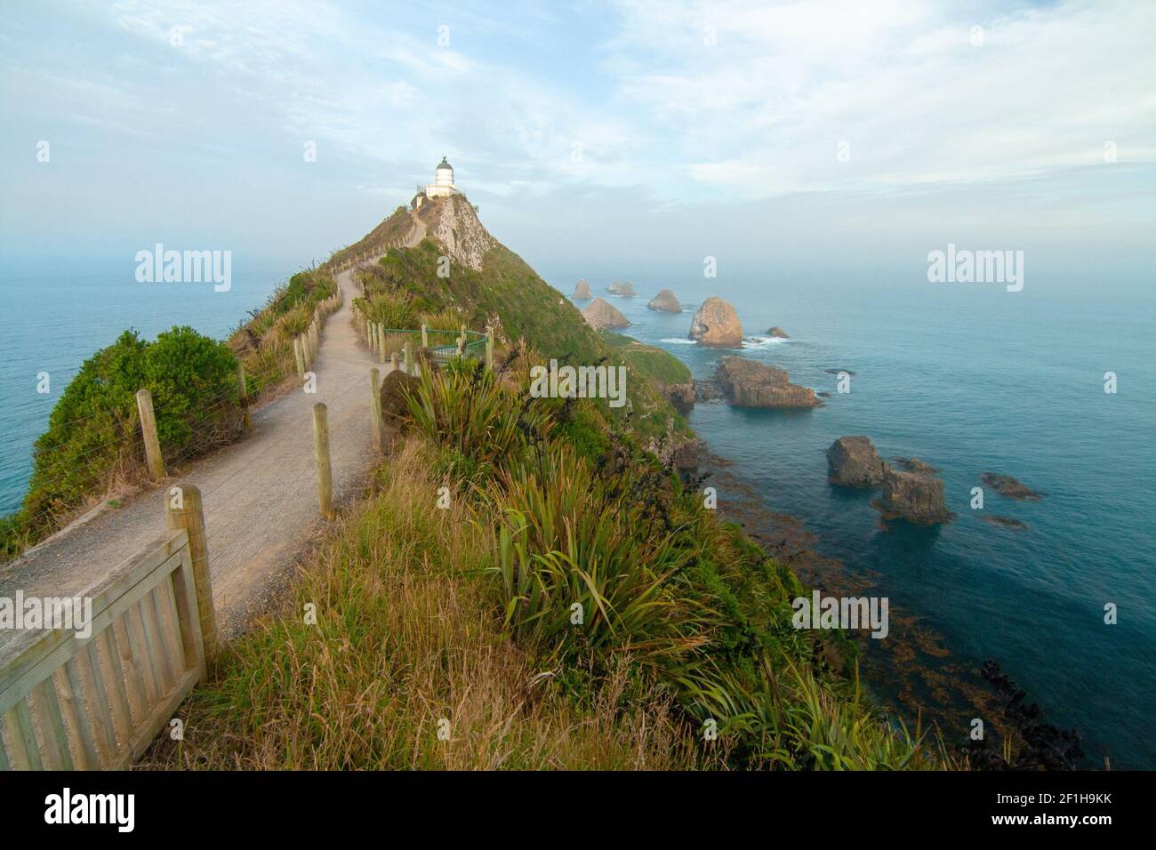 Faro di Nugget Point e famosi isolotti rocciosi (i Nuggets) sulla costa dell'Oceano Pacifico, tokata Walk, Southland Nuova Zelanda Foto Stock