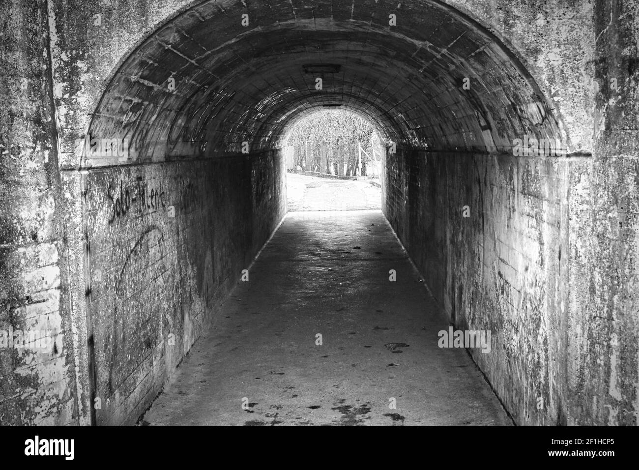 Un'immagine in scala di grigi di un tunnel con vecchie pareti in pietra Foto Stock