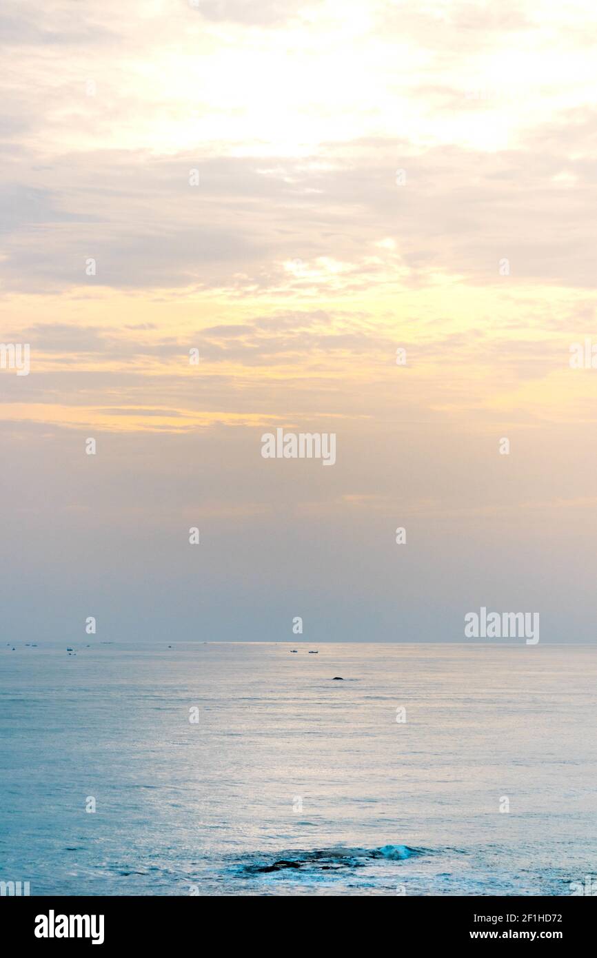 Una vista affascinante dell'oceano calmo che brulica sotto tramonto nel cielo nuvoloso Foto Stock