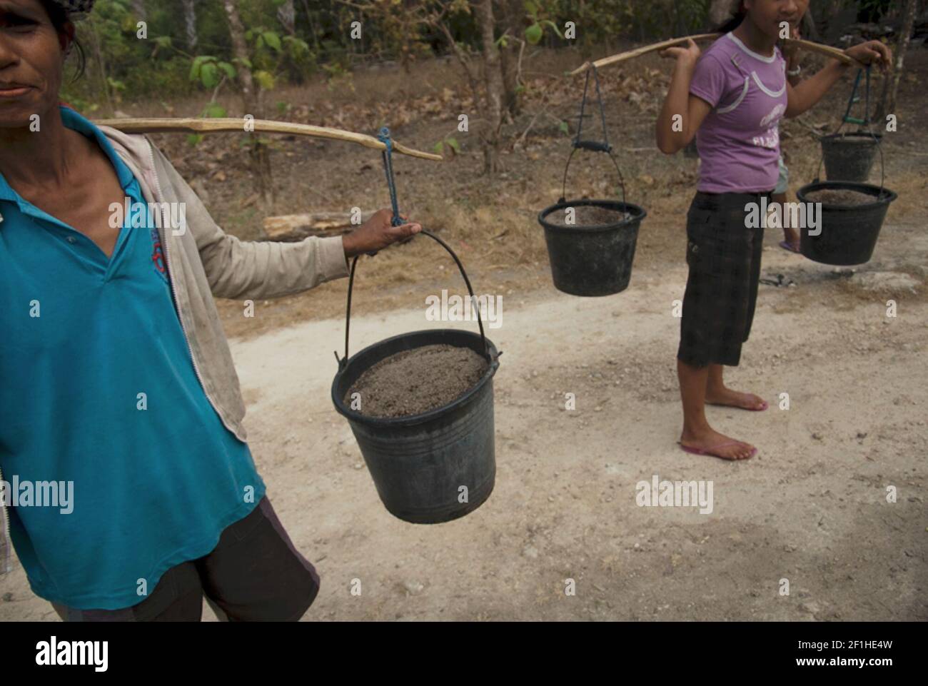 Donne che trasportano i secchi di plastica contenenti le sabbie per il progetto di costruzione della casa a Rote Island, Rote Ndao, Nusa Tenggara orientale, Indonesia. Foto Stock