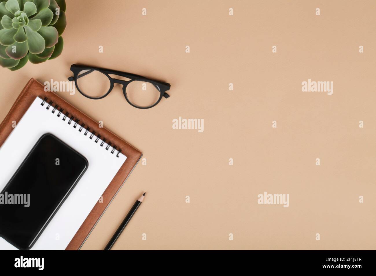 scrivania da tavolo per ufficio, area di lavoro con telefono cellulare, notebook, matita, piante verdi e occhiali. Background aziendale. Disposizione piatta, spazio di visualizzazione superiore.copia Foto Stock
