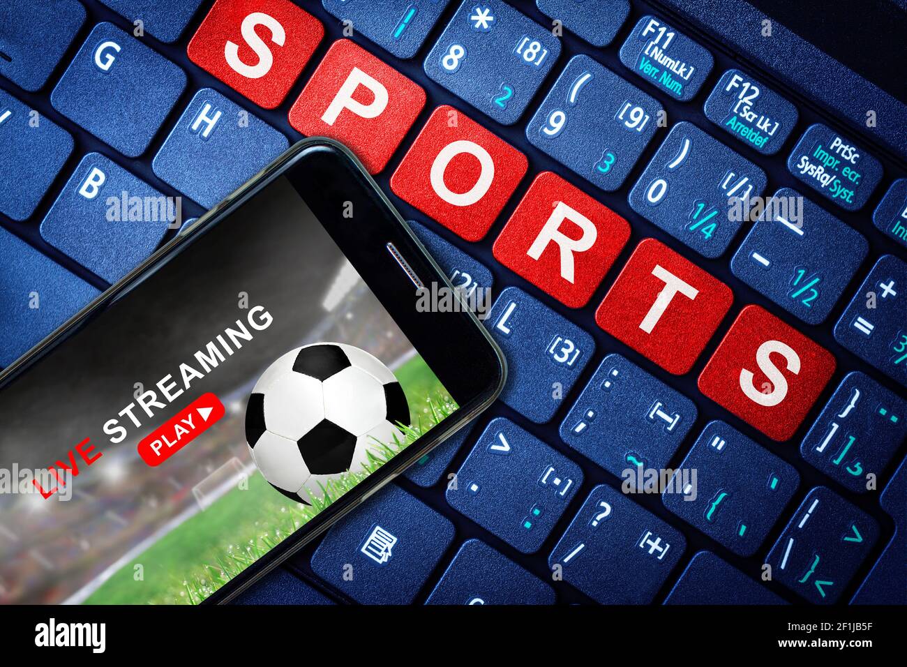 Sport Live streaming concetto che mostra Calcio o partita di calcio in trasmissione su smartphone con laptop high tech background. Accessibile su richiesta in digitale c Foto Stock