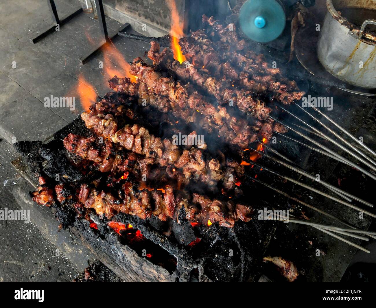 Satay di capra su fuoco rosso che grigliano dalla gente. Cibo indonesiano tradizionale fatto da montone. Foto Stock