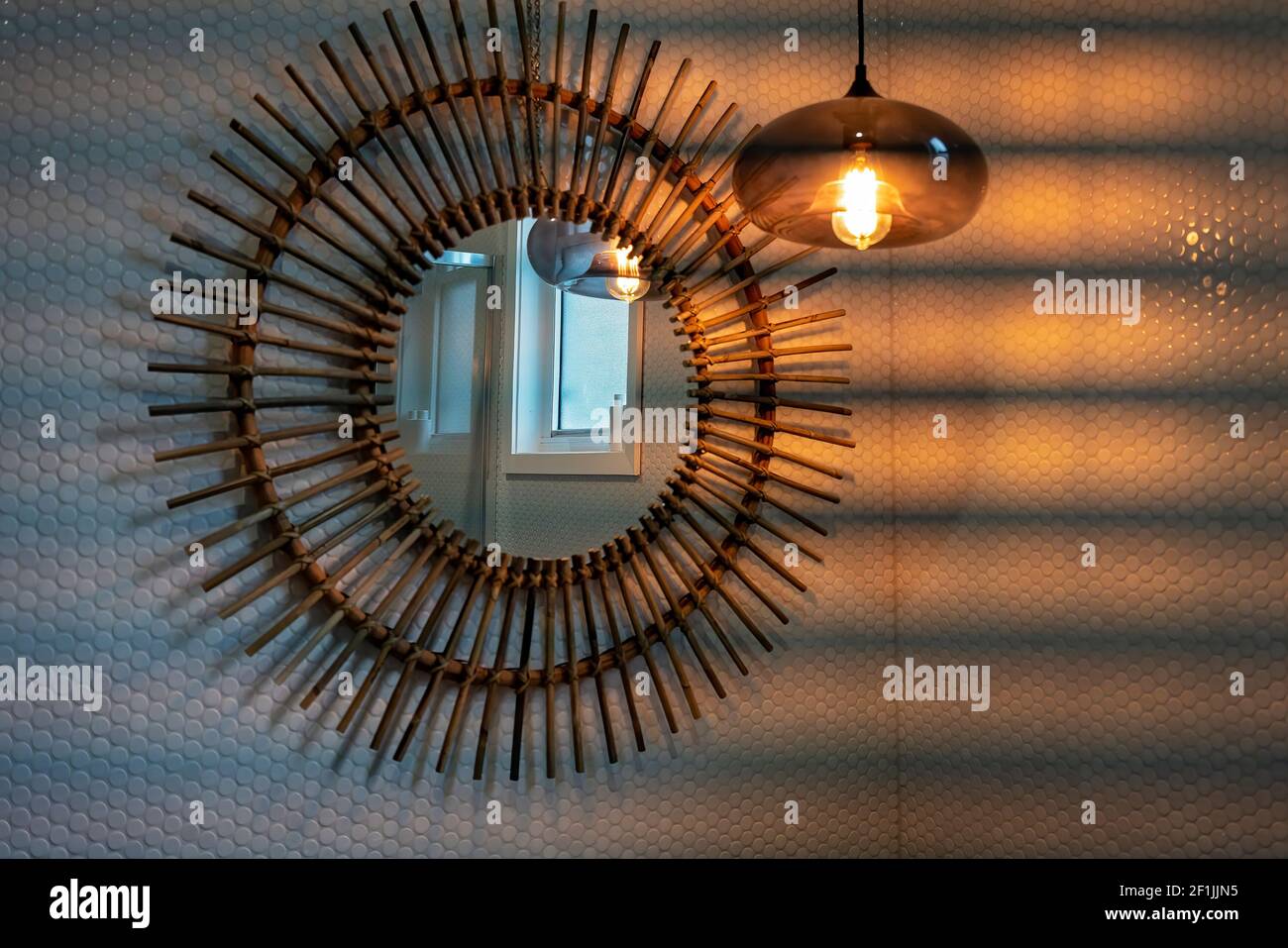 La luce appesa emette una luce soffusa su un bagno decorativo specchio su  una parete piastrellata Foto stock - Alamy