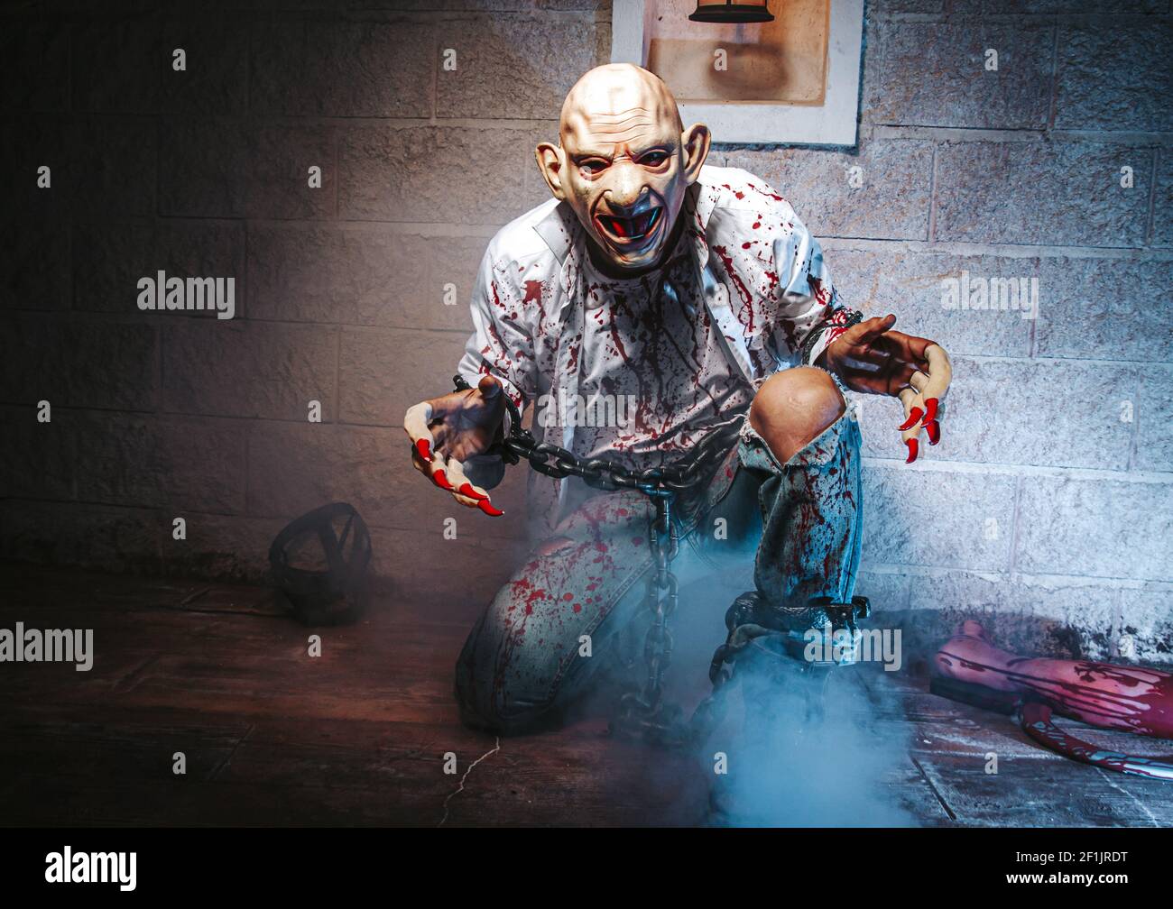 Costume di Halloween, uomo incatenato con sangue e coltello, uomo di zombie morte il fantasma orrore drenare la pelle di sangue di mano sta urlando darkne Foto Stock