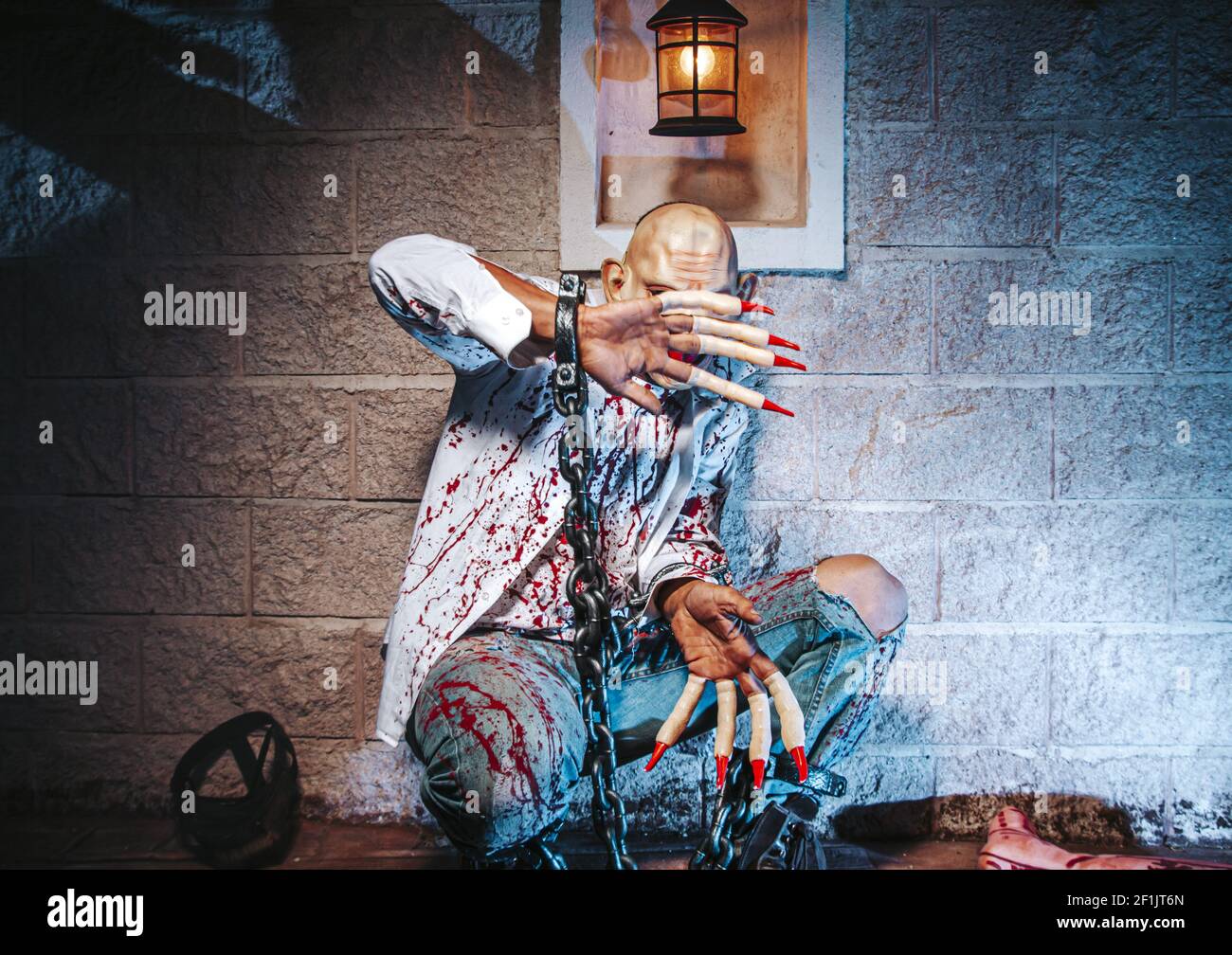 Costume di Halloween, uomo incatenato con sangue e coltello, uomo di zombie morte il fantasma orrore drenare la pelle di sangue di mano sta urlando darkne Foto Stock