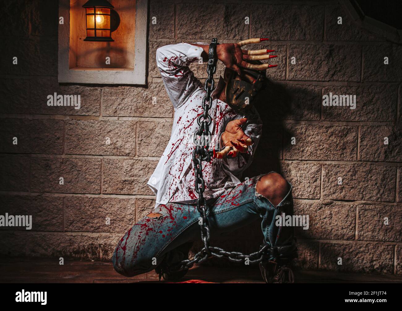Costume di Halloween, uomo incatenato con sangue e coltello, uomo di zombie morte il fantasma orrore drenare la pelle di sangue di mano sta urlando darkne Foto Stock