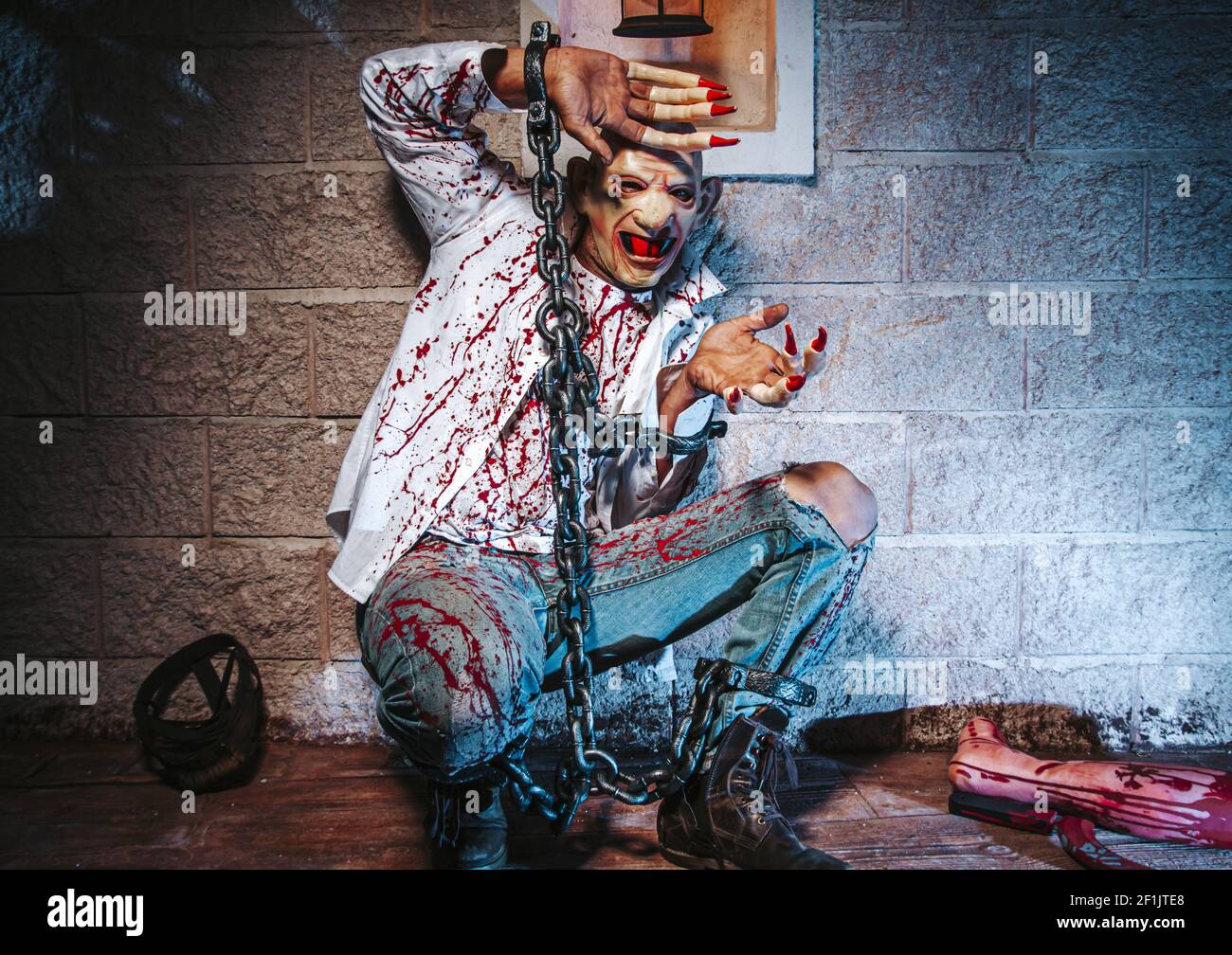 Costume di Halloween, uomo incatenato con sangue e coltello, uomo di zombie morte il fantasma orrore drenare la pelle di sangue di mano sta urlando darkne Foto Stock