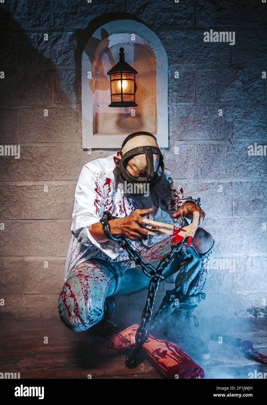 Costume di Halloween, uomo incatenato con sangue e coltello, uomo di zombie morte il fantasma orrore drenare la pelle di sangue di mano sta urlando darkne Foto Stock